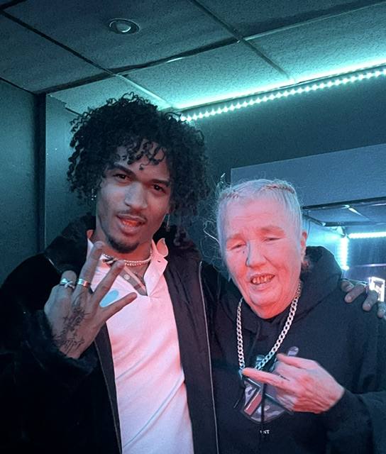 Two artists posing together under teal lights at Aunty Gale at The Bank