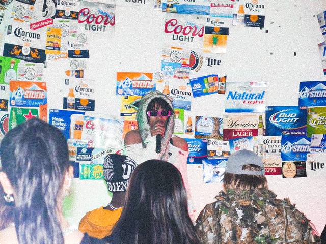 Performer in front of a wall covered in beer boxes at the Shepherdstown Church Pop-Up