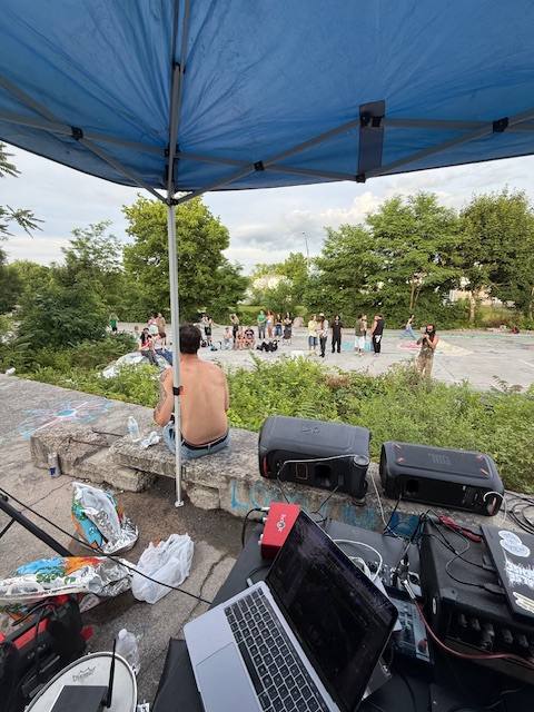 DJ setup under a blue canopy overlooking the crowd at the Skatepark Takeover Fundraiser